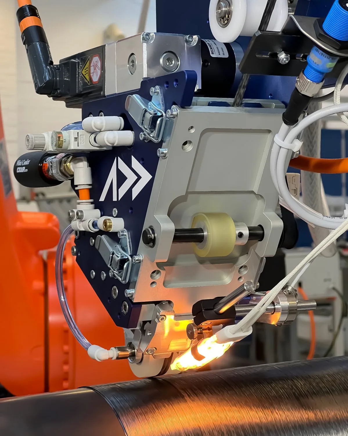 Addcomposites AFP-XS head laying carbon-fiber tow onto a rotating mandrel with a glowing nip point.
