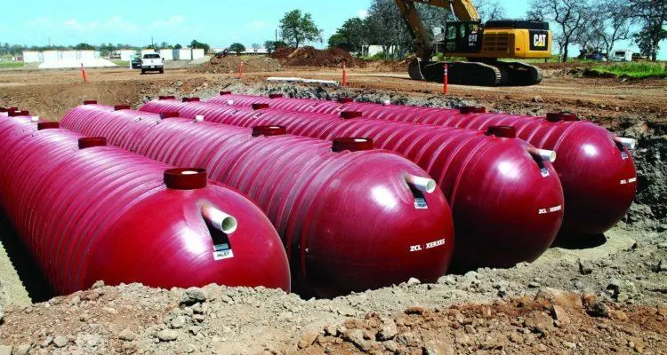 Large red cylindrical tanks in the groundDescription automatically generated with medium confidence