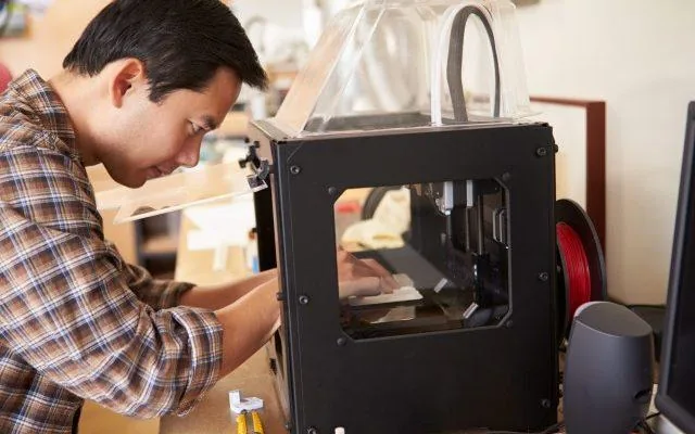 A person working on a 3d printerDescription automatically generated