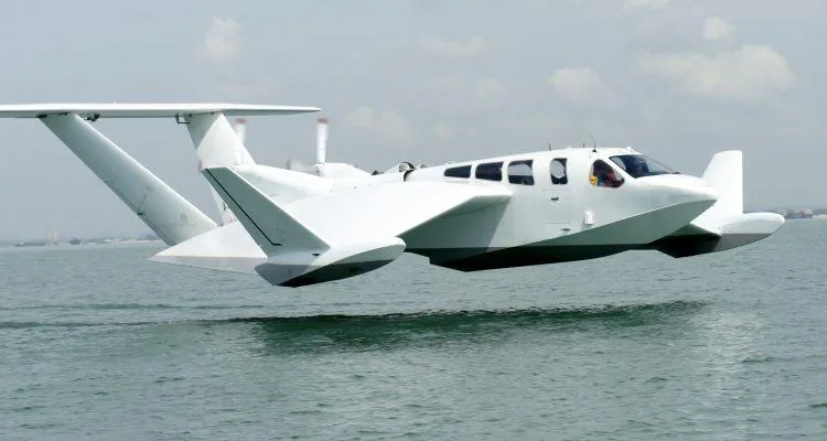 A white plane flying over waterDescription automatically generated