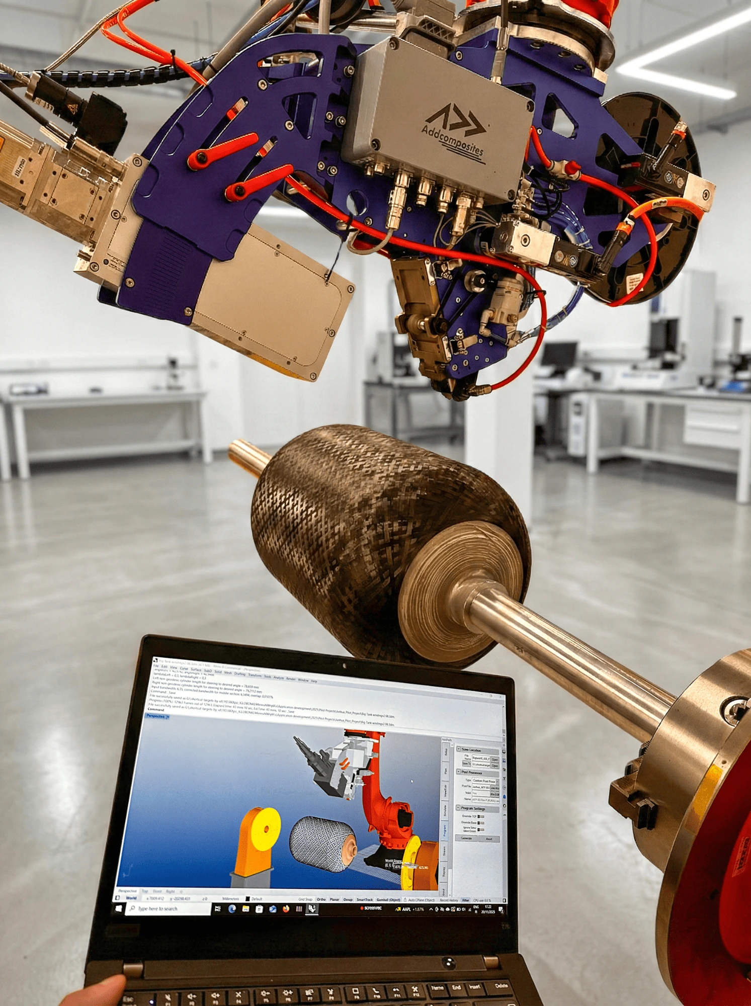 AddPath toolpath simulation on a laptop alongside AFP head and wet-wound carbon fiber cylinder