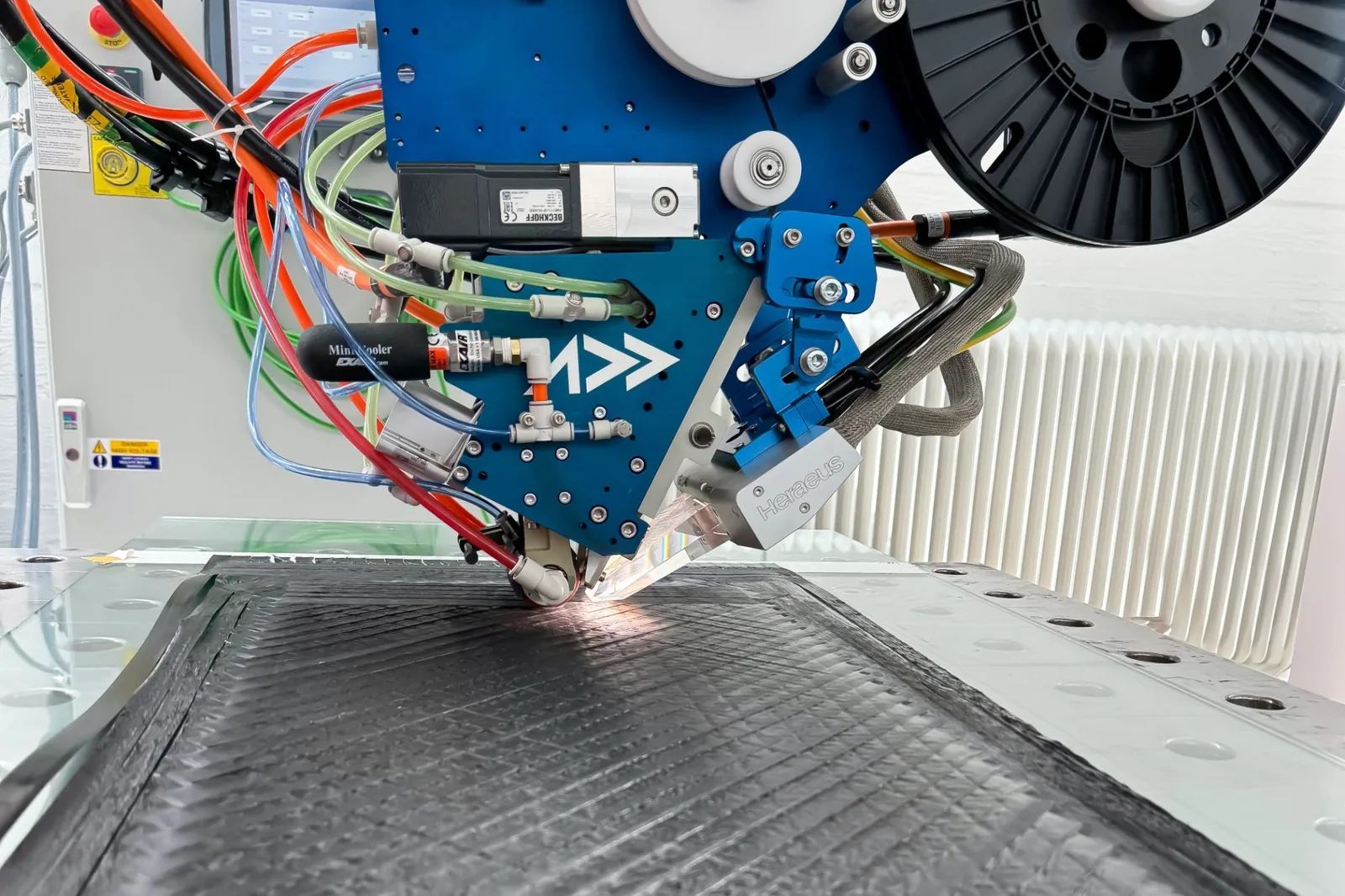 An Addcomposites AFP-XS toolhead places, orients, and consolidates carbon-fiber tow onto a laminate in a single pass.