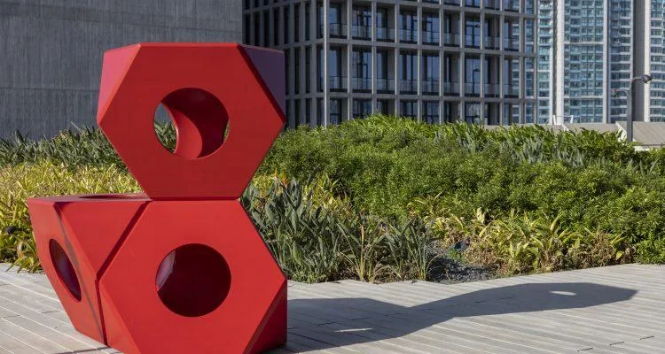 A red sculpture in front of a buildingDescription automatically generated