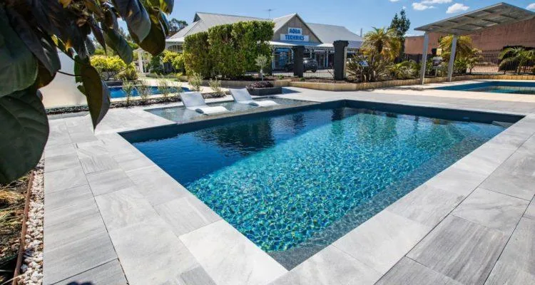 A pool with a deck and chairsDescription automatically generated with medium confidence