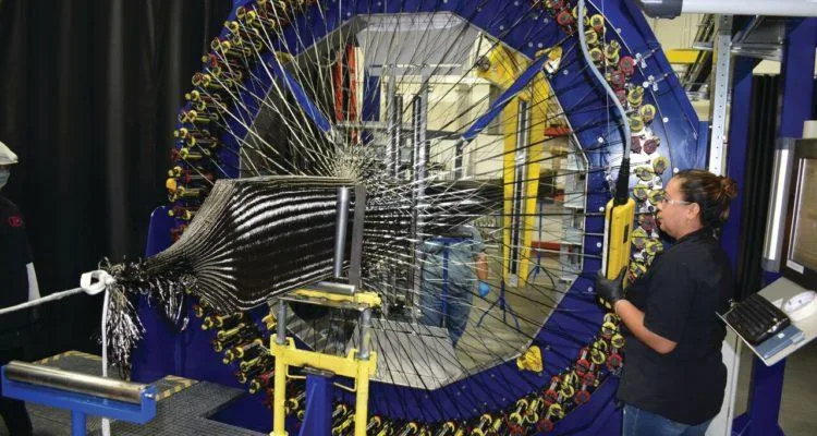 A person standing next to a large machineDescription automatically generated