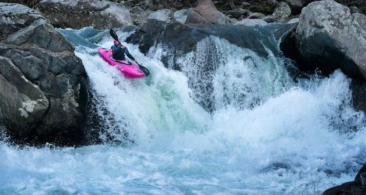 A person in a kayak on a riverDescription automatically generated