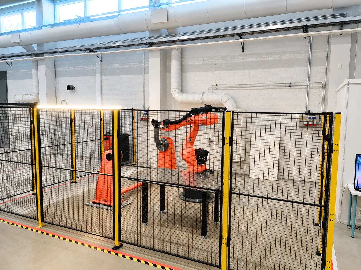 Complete AddCell installation with two KUKA robots, external axis, process tooling and safety enclosure